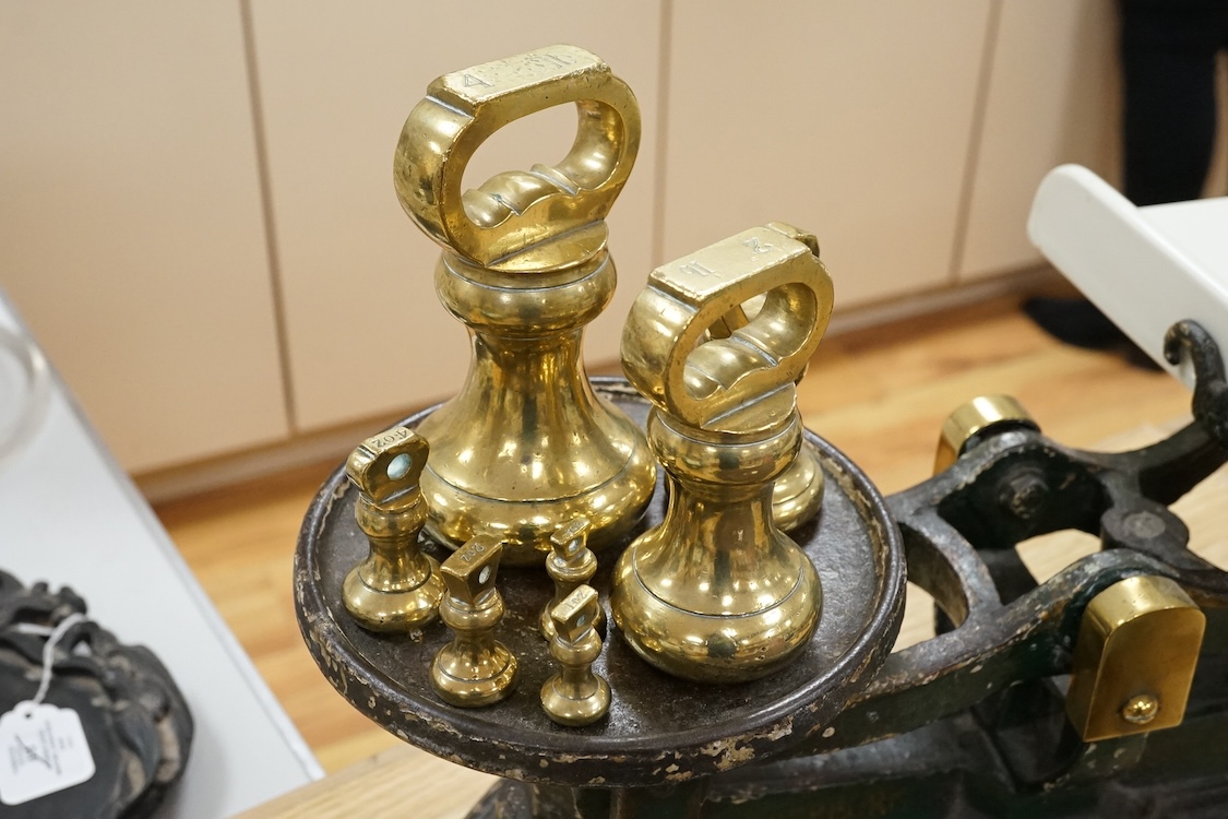 A set of Victorian iron and ceramic scales and seven brass weights, 53cm wide